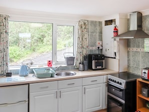 A kitchen with a window, a kettle, a toaster, a sink, and a stove. - Wren Cottage Apartment (Fishguard)