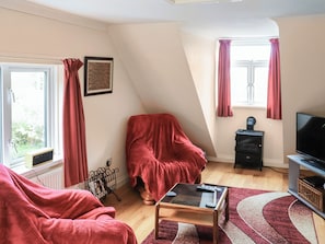 A room with a bed, a TV, a small table, and a window with curtains.