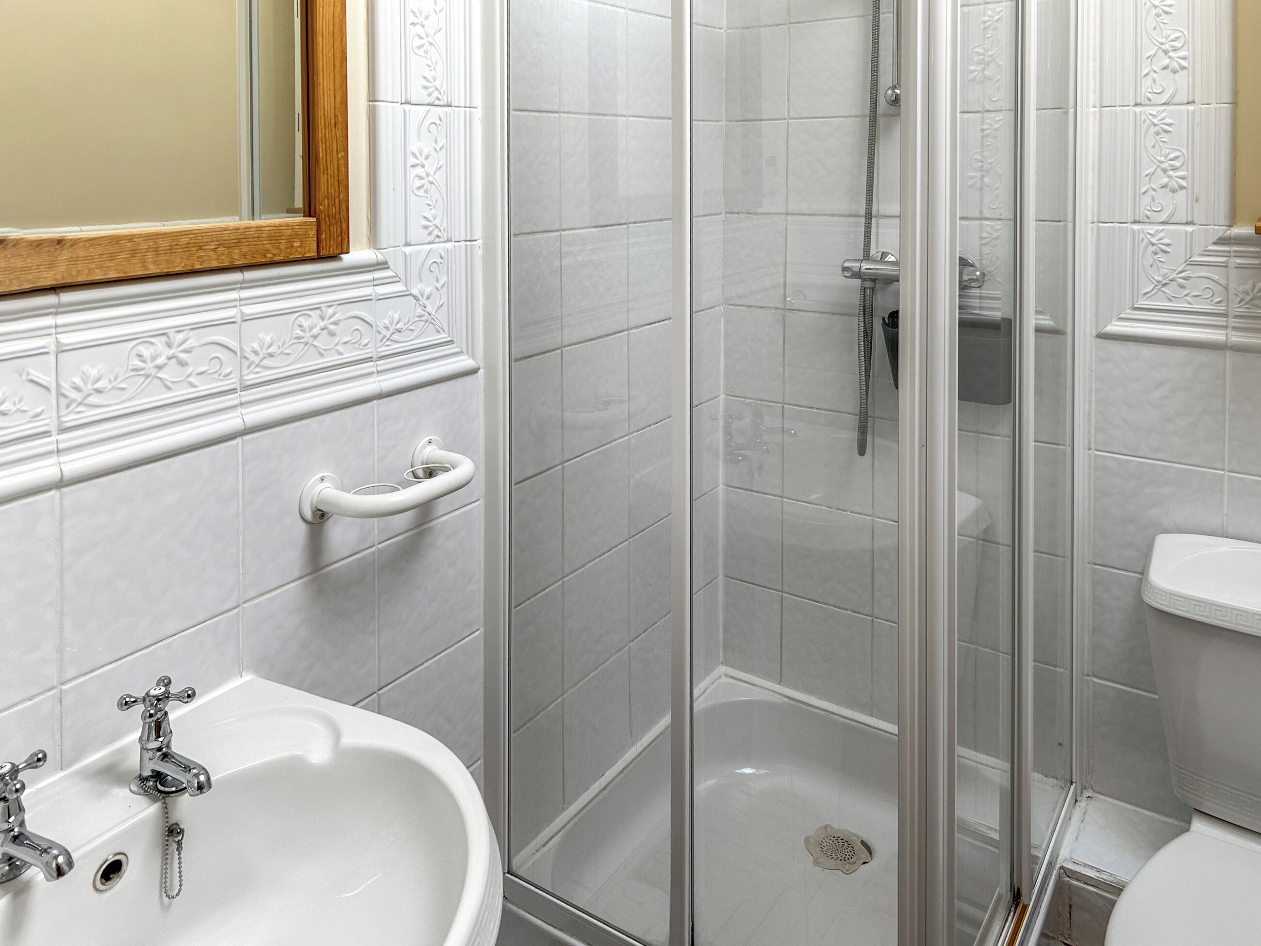 Un bagno con un lavandino bianco, box doccia in vetro e un water.