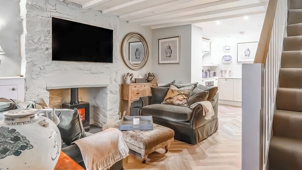 Ein modernes Wohnzimmer mit Kamin, flachbildfernseher an der Wand, Sofa und Couchtisch.