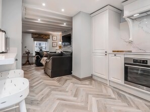 A modern kitchen with white cabinetry, a herringbone-patterned floor, and a built-in oven. - 1 bedroom accommodation in Conwy (Conwy)