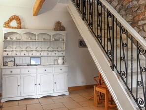 Eine Treppe mit schwarzen schmiedeeisernen Geländern, eine weiße Holzkabine mit Schubladen und Regalen sowie eine Steinsäule im Hintergrund.