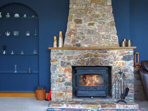 Ein Kamin aus Stein mit Feuer, Regale mit Gläsern und eine blaue Wand.