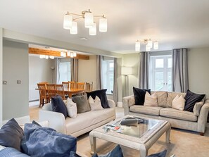 Ein geräumiges Wohnzimmer mit zwei Sofas, einem Couchtisch und einem Essbereich mit Holztischen und einer Tischplatte.