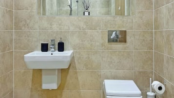 Een badkamer met een wastafel, spiegel, toilet en een klein spiegeltje boven het toilet.