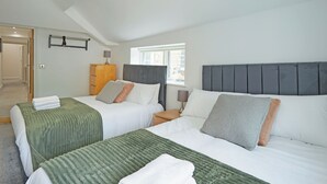 Een hotelkamer met twee bedden, een houten dressoir, een raam en een kapstok.