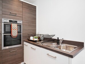 A modern kitchen with a built-in oven, a stainless steel sink, and wooden cabinetry. - 5 bedroom accommodation in Harrogate (Harrogate)