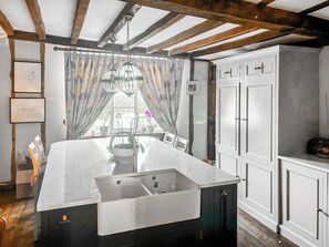 A kitchen with a large island, white cabinets, and a window with curtains. - 8 bedroom accommodation in Witnesham (Witnesham)