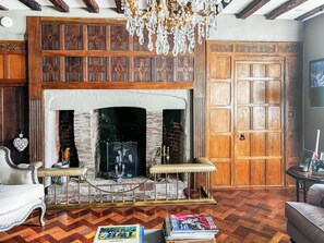 A room with a fireplace, wooden paneling, a chandelier, and a door. - 8 bedroom accommodation in Witnesham (Witnesham)