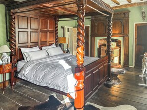 A four-poster bed with a wooden frame and a central column, a nightstand with a lamp, and a small decorative vase. - 8 bedroom accommodation in Witnesham (Witnesham)