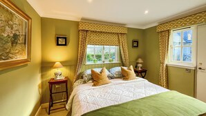 Quarto com cama, duas mesas de cabeceira, janela com cortinas e decoração nas paredes.