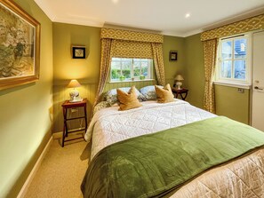 Ein Schlafzimmer mit einem Bett, zwei Nachttischen, einem Fenster mit Vorhängen und Wandbildern.