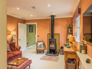 Ein gemütliches Wohnzimmer mit Kamin, einer Couch, einem Couchtisch und einer Lampe.