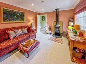 A living room with a sofa, a coffee table, a fireplace, a chair, and a lamp. - 1 bedroom accommodation in Strathtay (Strathtay)