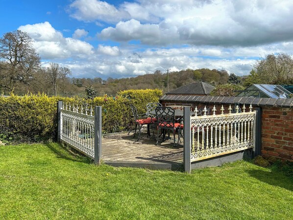 Un jardin clos, agrémenté d  ’un belvédère, d’un bâtiment en briques et d’un ciel dégagé.