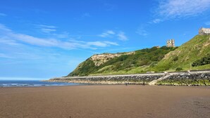 Ein Strand mit einer Steinmauer und einer Burg auf einem Hügel.