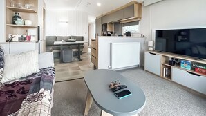 Kompakti oleskelutila, jossa on sohva, ruokapöytä, pieni keittiö ja televisio.
