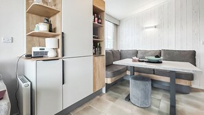 Moderni keittiö, jossa on integroidut kodinkoneet, ruokailutila penkillä sekä roskakori.