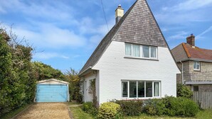 A house with a steeply pitched roof, a garage, and a well-maintained lawn. - Bembridge Coastal Escape (Bembridge)