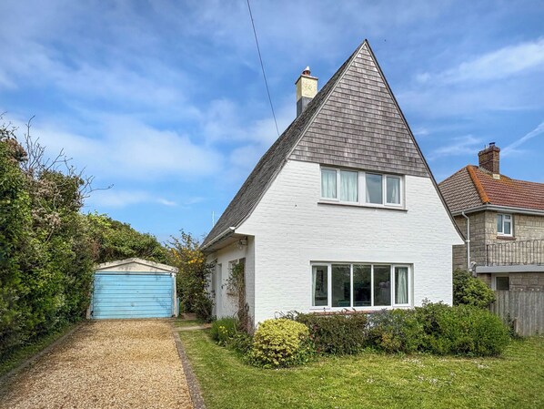 Une maison avec un toit à forte pente, un garage et une pelouse bien entretenue.