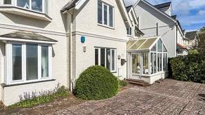 Een huis met twee verdiepingen, een erker, een tuinkamer en een geplaveid oprit.