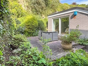 Ein modernes Haus mit Terrasse, einem kleinen Garten und einem Fenster mit Blick auf die umliegende Natur.