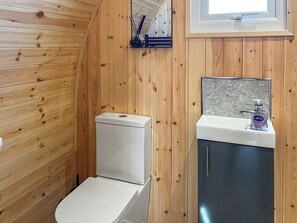 A wooden-paneled bathroom with a white toilet, a sink with a mirror, and a window above the sink. - 1 bedroom accommodation in Humanby, near Filey (Humanby, near Filey)