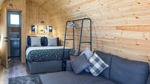 Una habitación acogedora con cama, sofá, una mesita y un sillón colgante.