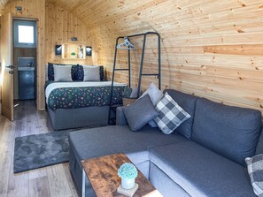 A cozy room with a bed, a sofa, a small table, and a hanging chair. - 1 bedroom accommodation in Humanby, near Filey (Humanby, near Filey)
