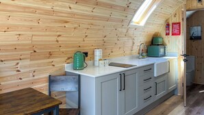 Una cocina compacta con detalles de madera, una encimera blanca y una pequeña mesa de comedor.