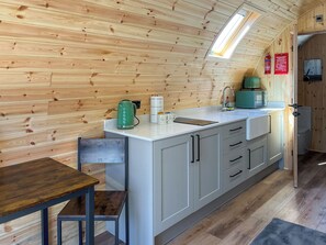 A compact kitchen with a wooden interior, a white countertop, and a small dining table. - 1 bedroom accommodation in Humanby, near Filey (Humanby, near Filey)