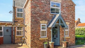 A brick house with a gabled roof, a front door, and a satellite dish. - Old Master's Cottage (Leven)