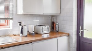 Eine Küche mit weißen Schränken, einem Toaster, einem Wasserkocher und einem Fenster mit Jalousien.
