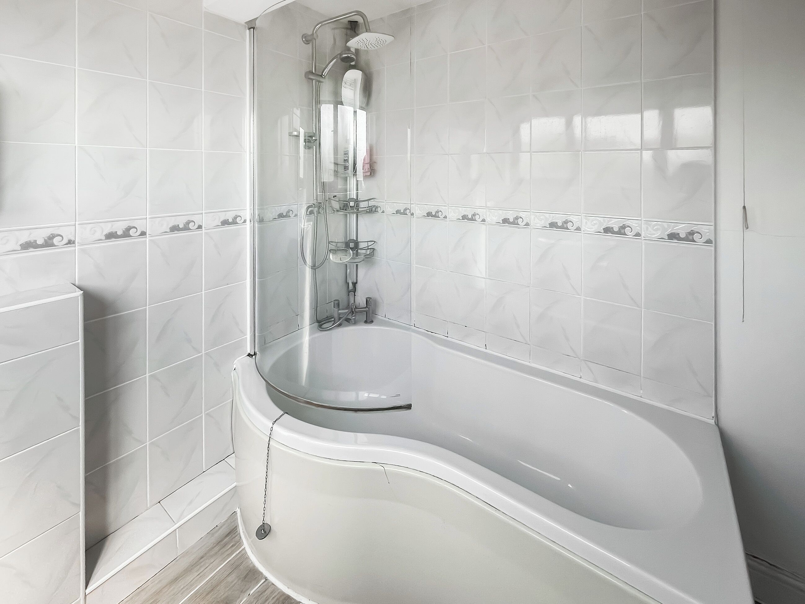 A modern bathroom with a freestanding bathtub, a glass-enclosed shower, and white tiled walls.