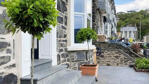 A stone building with a staircase leading to a door, a potted plant, and a clear sky.