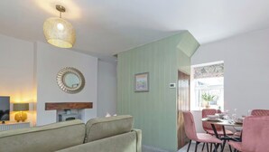A living room with a sofa, dining table with chairs, a TV, and a decorative mirror.