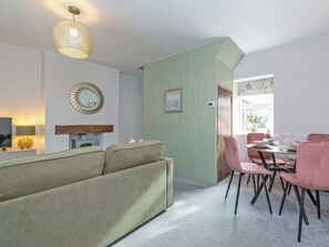 A living room with a sofa, dining table with chairs, a TV, and a decorative mirror.
