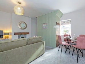 A living room with a sofa, dining table with chairs, a TV, and a decorative mirror. - 2 bedroom accommodation in Staindrop, near Barnard Castle (Staindrop, near Barnard Castle)