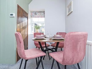 A dining area with a table set for four, pink upholstered chairs, and a window with a view of the outside. - 2 bedroom accommodation in Staindrop, near Barnard Castle (Staindrop, near Barnard Castle)