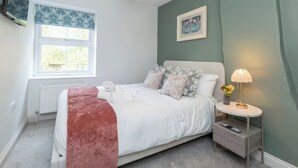 A bedroom with a bed, bedside table, lamp, and a window.