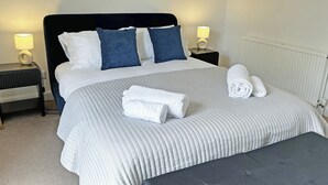 A neatly made bed with pillows, a bedside lamp, and a rolled towel on the bed. - A Cosy two bedroom cottage, perfectly located in Bamford. (Bamford)