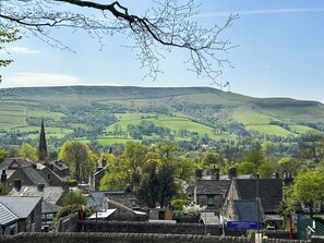 Un paysage rural caractérisé par des collines douces, le clocher d’une église et des bâtiments en pierre.