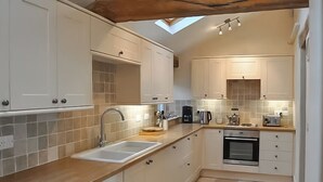 Una cocina moderna con armarios blancos, encimera de madera, tragaluz y horno empotrado.