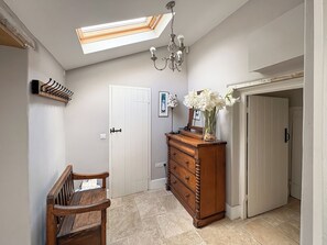 A hallway with a skylight, a wooden bench, a dresser, and a door. - Lower Park Farmhouse (Lyme Regis)