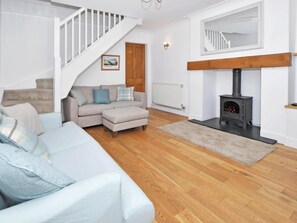 Ein Wohnzimmer mit weißer Treppe, einer Couch, einem Kamin und einer Heizung.