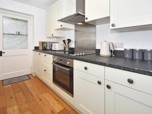 Eine moderne Küche mit weißen Schränken, einer Edelstahl-Dunstabzugshaube, einer Mikrowelle, einem Toaster und einem Wasserkocher.