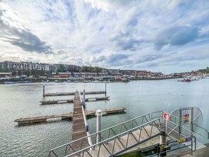A waterfront view with docks and boats, a pier extending into the water, and a town in the background. - Swallows Haven - UK51879 (Whitby)