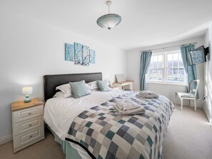 A bedroom with a bed, bedside tables, a desk, a chair, a window with curtains, and artwork on the wall. - Swallows Haven - UK51879 (Whitby)