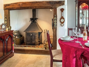 A traditional room with a stone fireplace, wooden beams, a dining table set with plates and glasses, and a clock on the wall. - 2 bedroom accommodation in Barrington, near Ilminster, (Barrington, near Ilminster,)