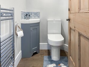 Une salle de bain équipée de toilettes, d’un lavabo, d’un porte-serviettes et d’une porte en bois.